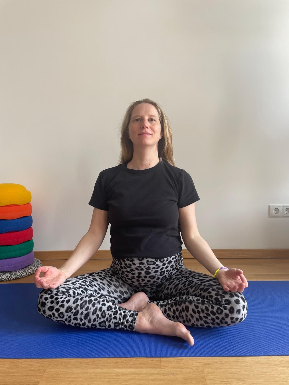 Lena Hagemann sitzt mit offenen Händen in einer Meditationshaltung auf ihrer Yogamatte